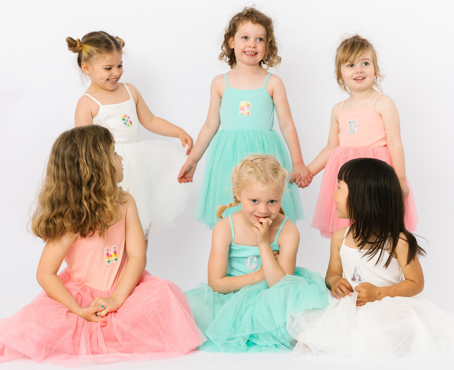 Girls wearing tutu dresses personalised with the first letter of the child’s name stitched onto the front of them